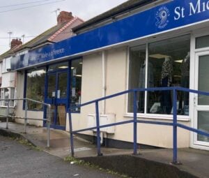 Blue and white fronted shop with blue railings leading to the front door.