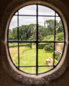 A garden seen through a circular window, offering a picturesque view of nature's beauty.