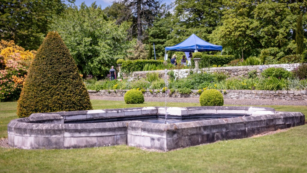 A serene outdoor scene with a fountain surrounded by lush greenery