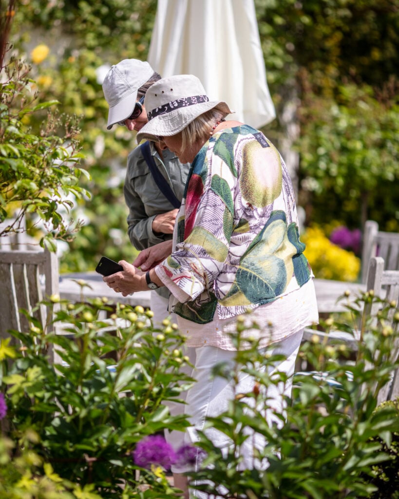 Two individuals standing amidst lush greenery in a serene garden setting.