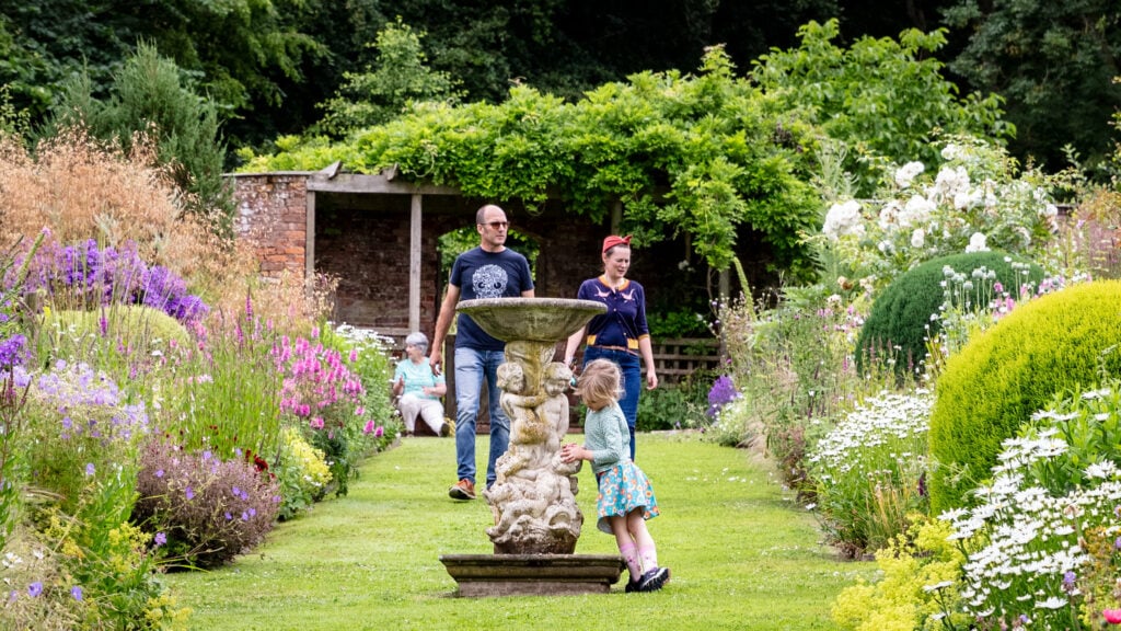 A family posing in a garden near a fountain.