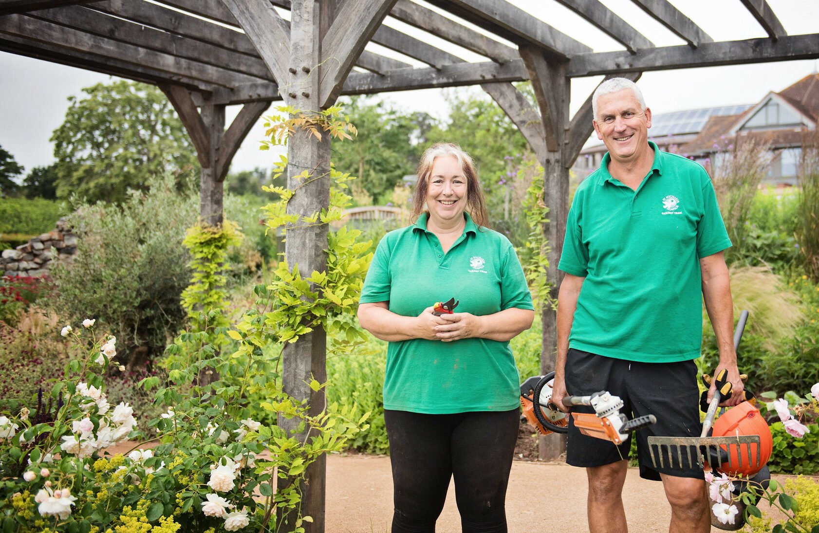 Two volunteer gardeners, posed in the Hospice gardens ready to work