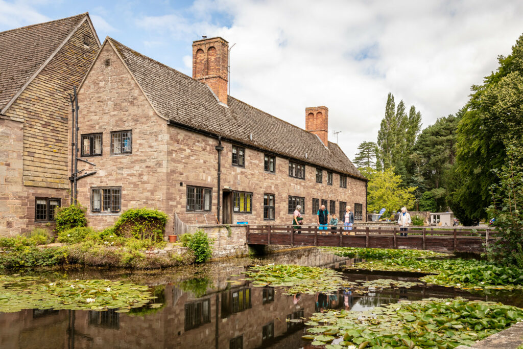 A grand building with a bridge spanning a serene pond.