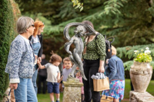 A group of individuals gathered around a statue in a serene garden setting.