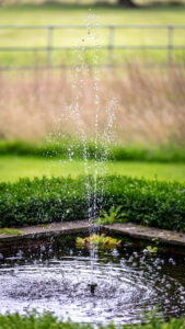 A serene park fountain with a fence in the background, creating a peaceful and picturesque scene.