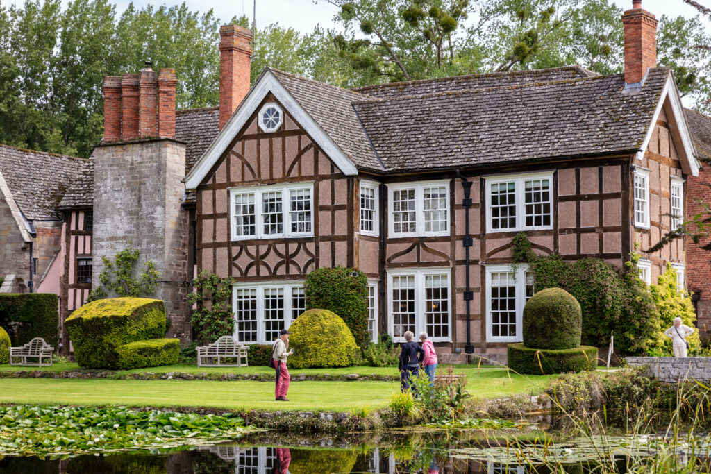 A spacious house with a serene pond in front, creating a picturesque view.