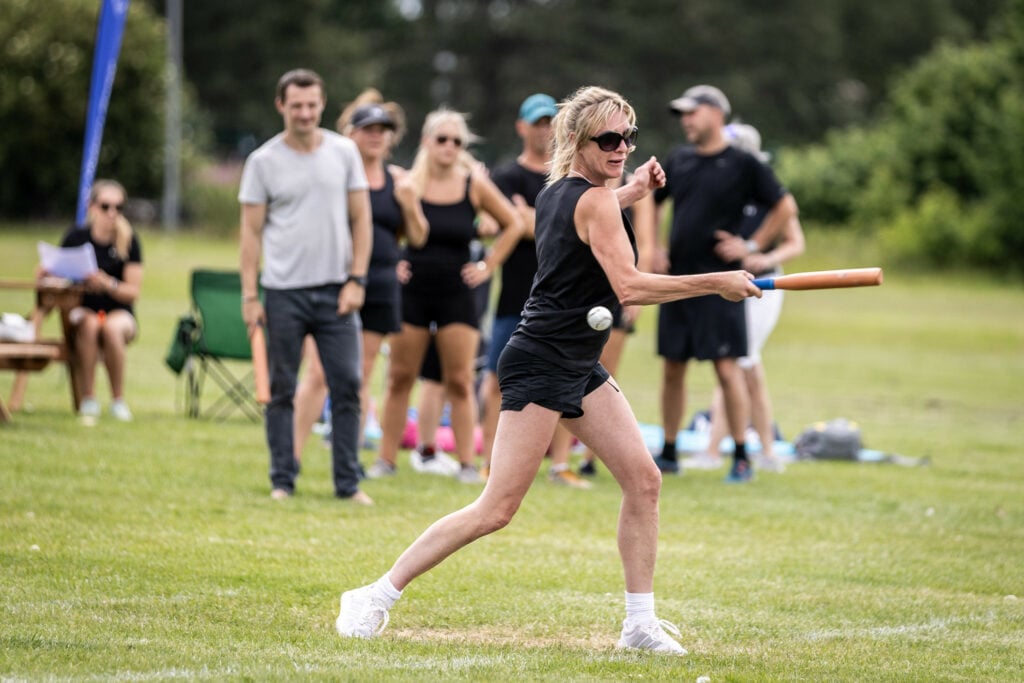 Lady holding rounders bat, about to swing to hit the ball.