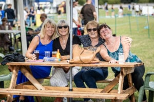 a group of ladies sitting on a bench and spectating at the Sue Parry Football Festival