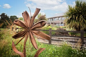 A metal flower sculpture stands tall amidst a vast field, showcasing its intricate design and artistic beauty.