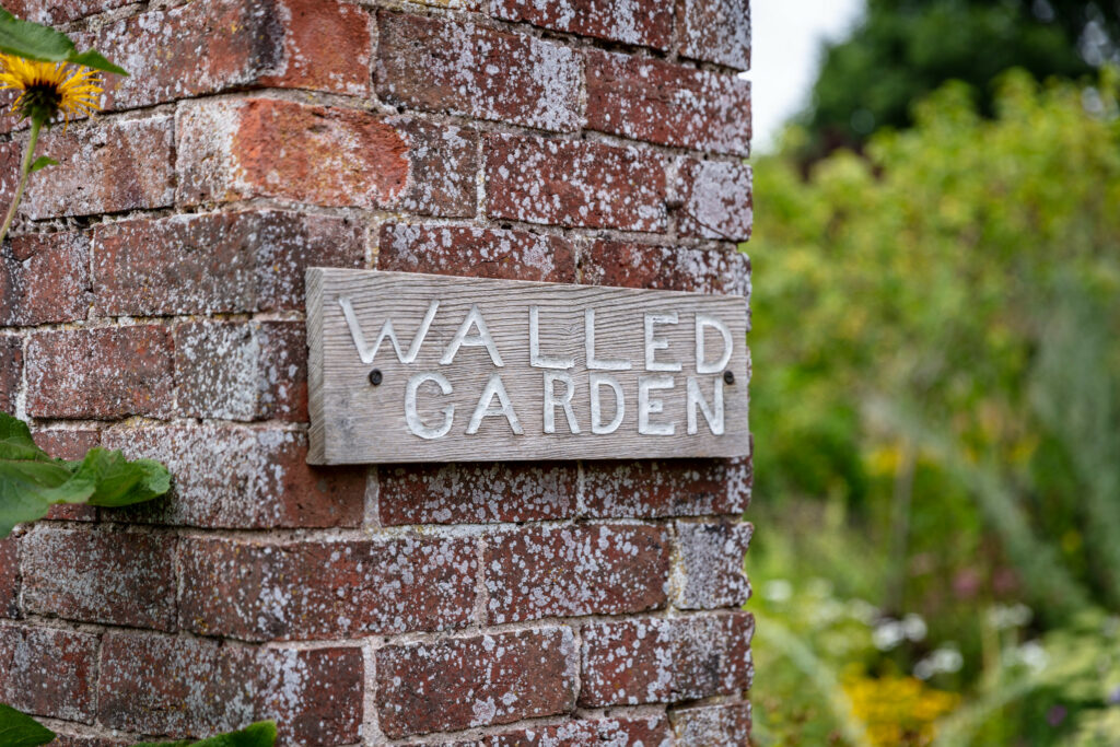 A beautiful outdoor wedding ceremony surrounded by lush greenery and colorful flowers in a walled garden.