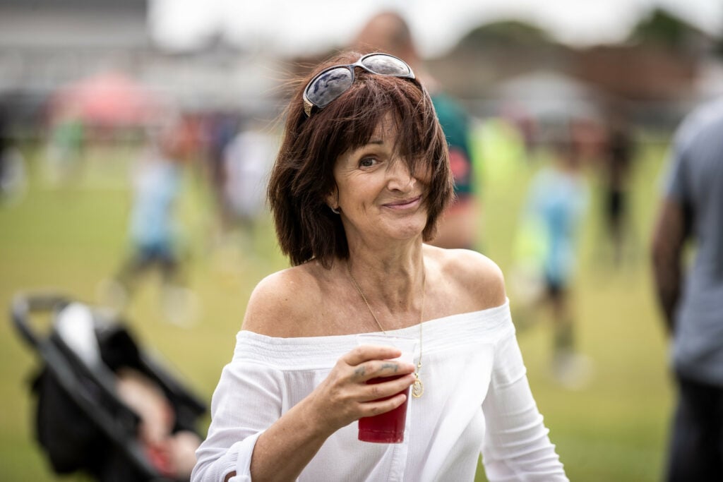 A woman holding a drink at a festival, enjoying the lively atmosphere.