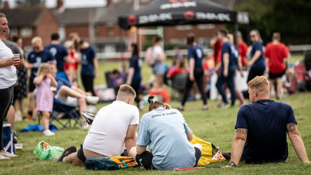 Spectators enjoying a sporting event, sitting on the grass.