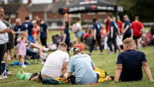 Spectators enjoying a sporting event, sitting on the grass.